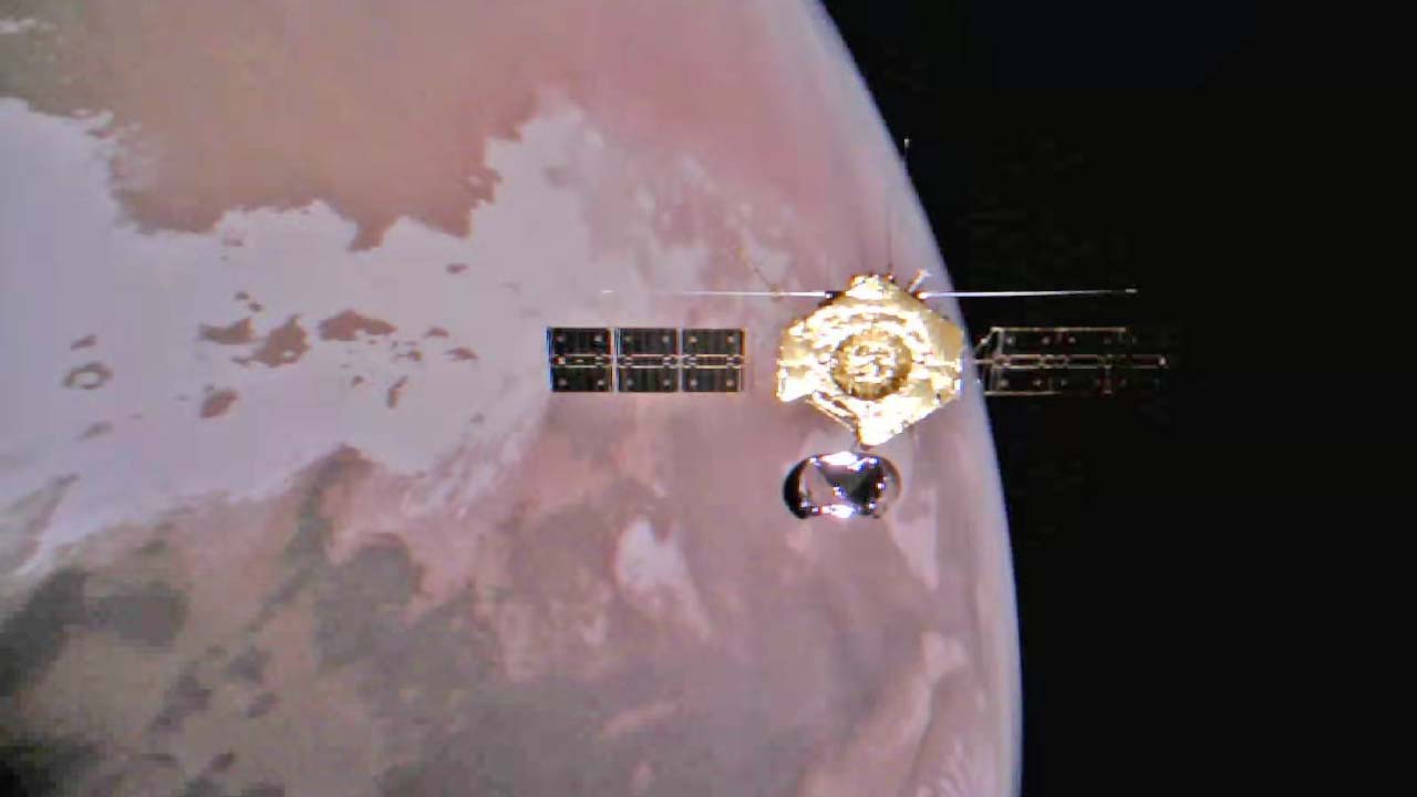 La sonda Tianwen 1 en órbita alrededor de Marte observada por una cámara desplegable con el planeta al fondo