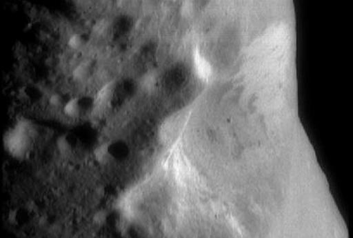 Vista oblicua del gran cráter central de Eros tomada por NEAR Shoemaker, mostrando variaciones de albedo y bloques en su interior.