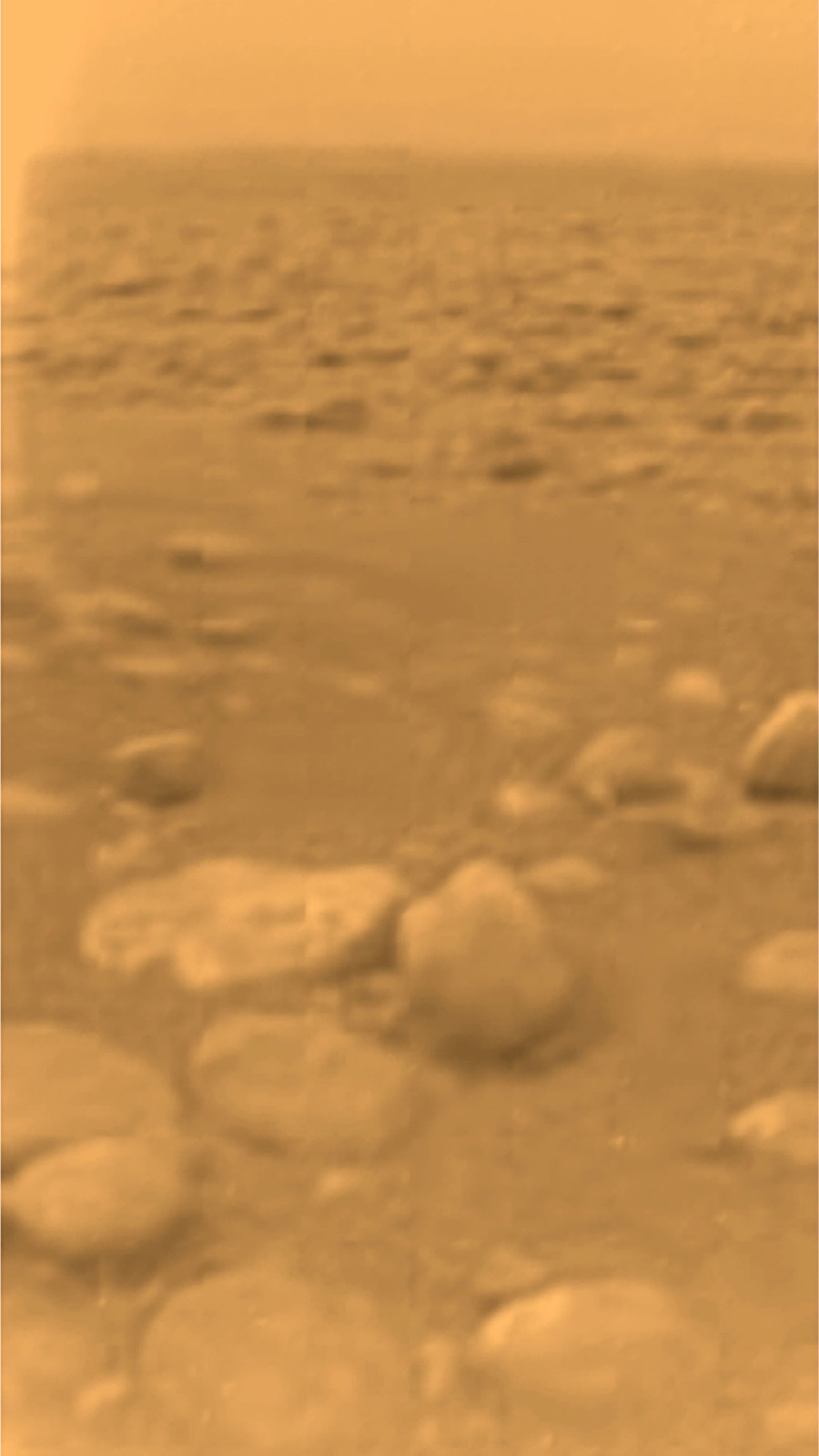 Primera imagen en color de la superficie de Titán tomada por la sonda Huygens mostrando cantos redondeados de hielo sobre el terreno