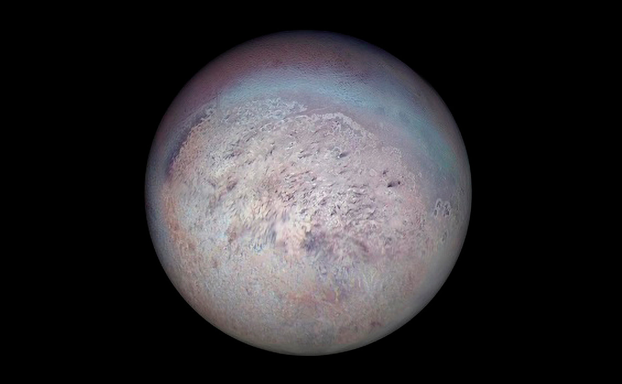 Imagen de Tritón obtenida por Voyager 2 donde se observan trazas oscuras generadas por penachos de nitrógeno en la región polar sur.