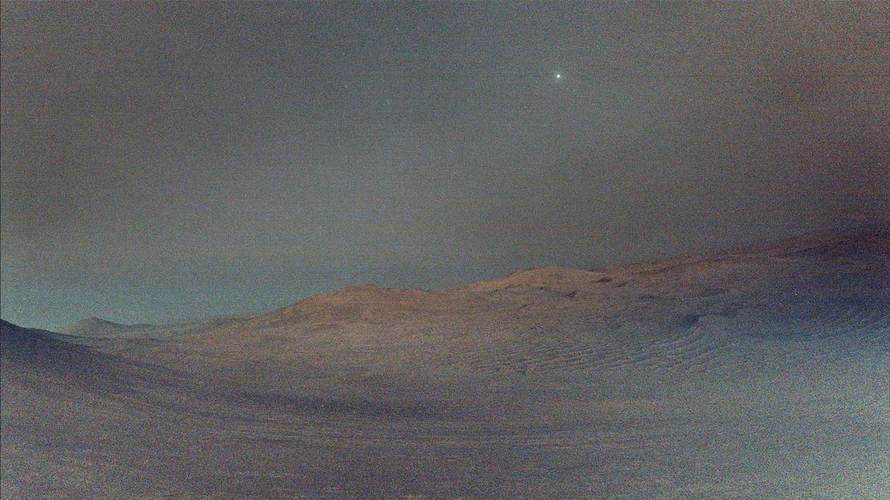 El rover Perseverance de la NASA captura a Deimos, la luna más pequeña de Marte, brillando en el cielo antes del amanecer sobre el paisaje marciano.